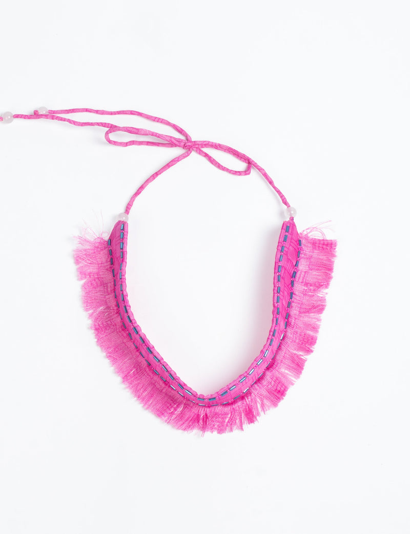 Pink fabric tie-up choker with fringe edges and blue bead embellishments, shown flat on white background