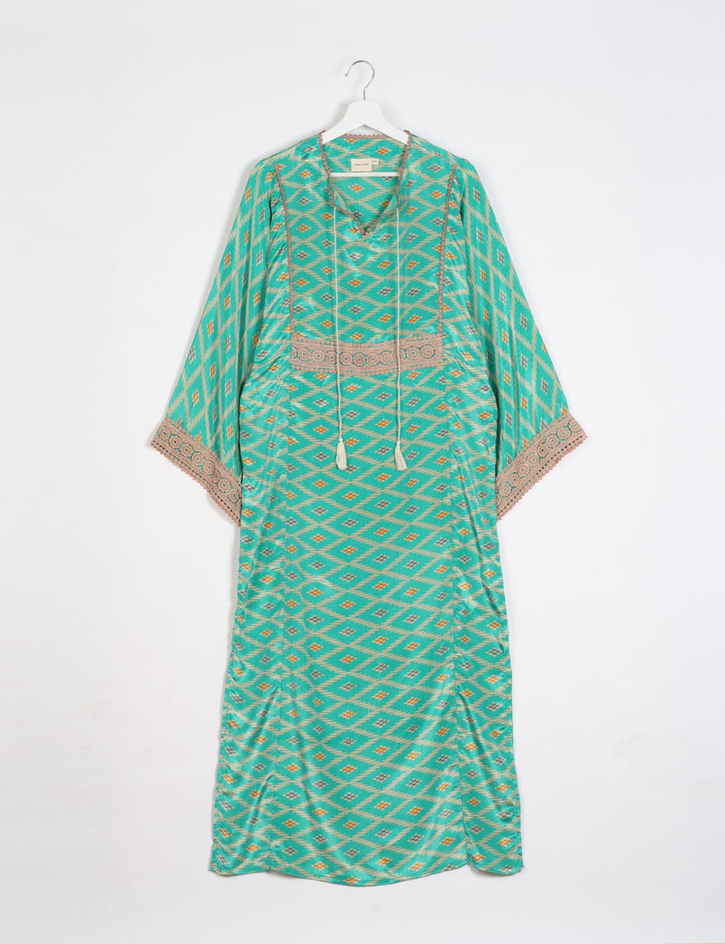 Green maxi kaftan with geometric diamond pattern, beige lace trim on sleeves and chest, hanging on white hanger