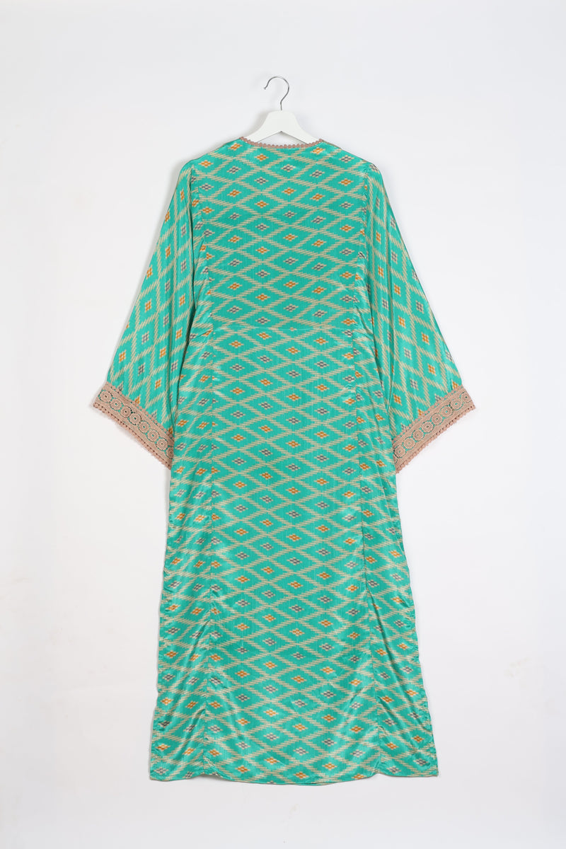 Green maxi kaftan with geometric diamond pattern, beige lace trim on sleeves, shown from back on white hanger