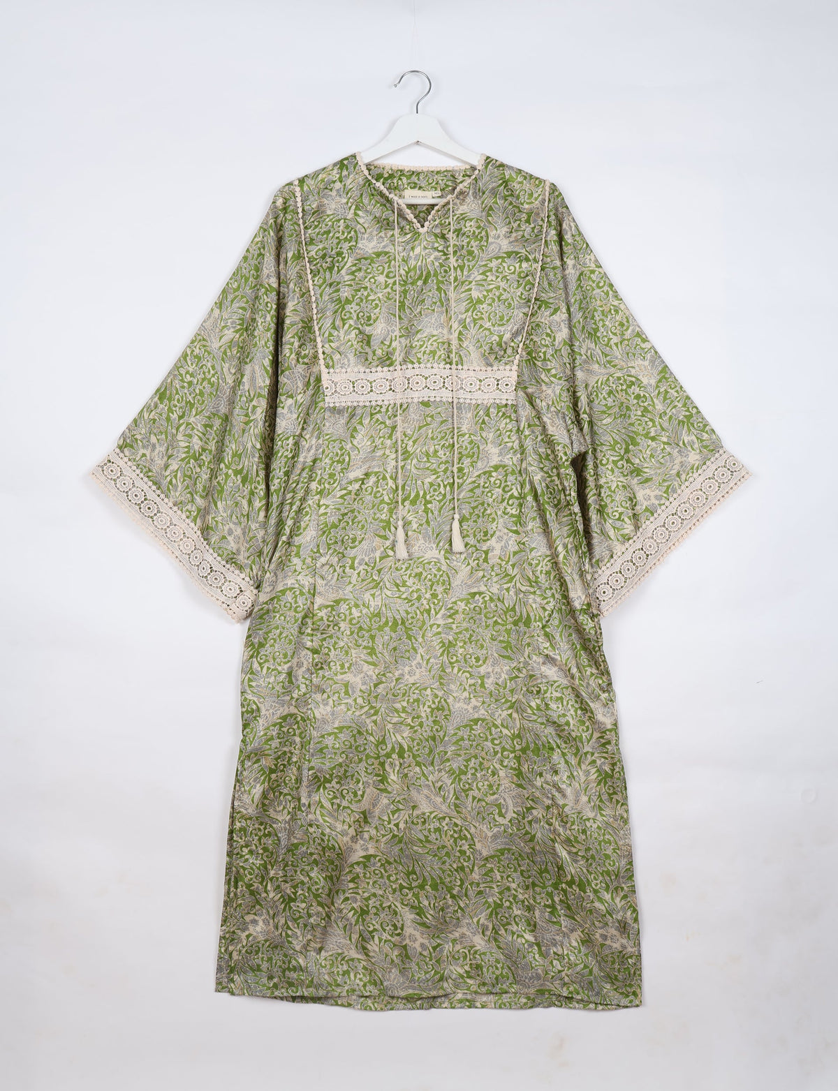Green tropical maxi kaftan with beige lace trim on sleeves and chest, V-neck with tassel ties, hanging on white hanger