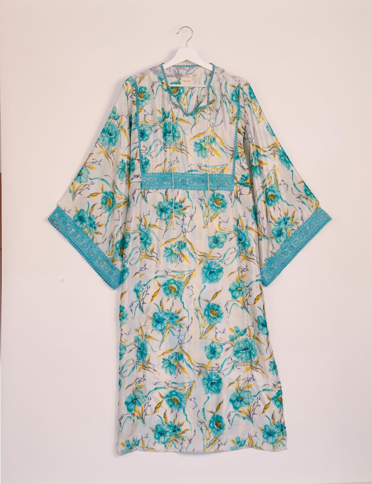 Maxi Kaftan with cotton lace on sleeves and midriff, featuring a tie-up neckline with tassels. Ankle-length, eco-friendly fashion made from recycled materials, offering sustainable women’s clothing for a chic, earth-friendly wardrobe.