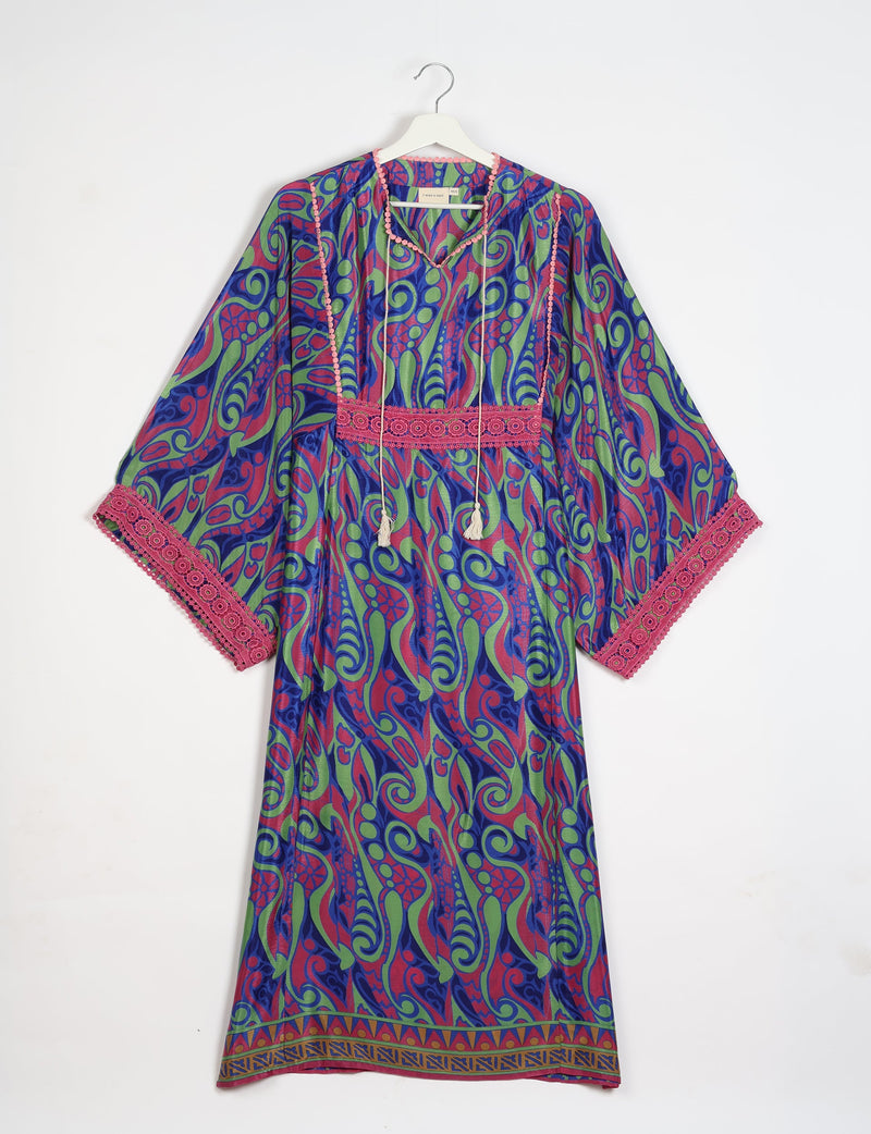 Maxi kaftan with blue, green, and red abstract swirl pattern, pink lace trim on sleeves and waist, hanging front view