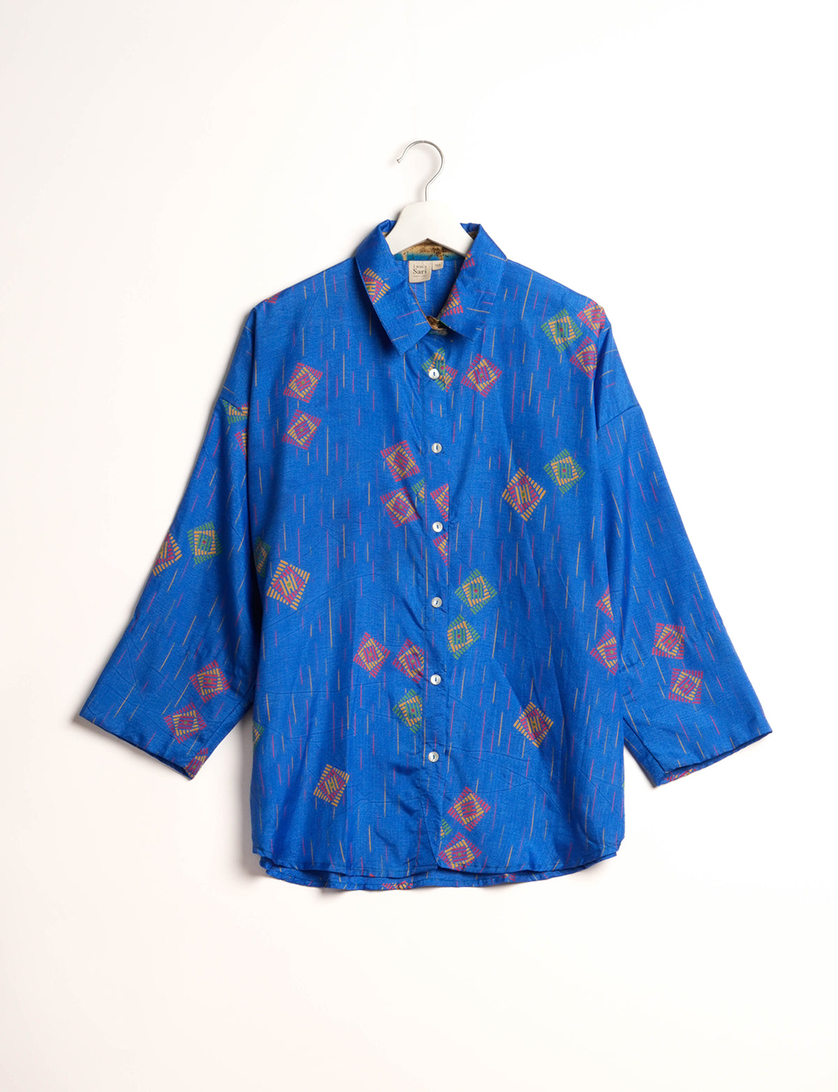 Experience chic comfort with our OVERSIZED SHIRT – a one-of-a-kind piece crafted from sari waste by talented Indian female artisans. With 3/4 length sleeves, a regular shirt collar, and a contrasting inner collar band, this shirt is perfect for work or casual hangouts. Versatile and stylish, it pairs effortlessly over a shift dress, jumpsuit, or with pants.