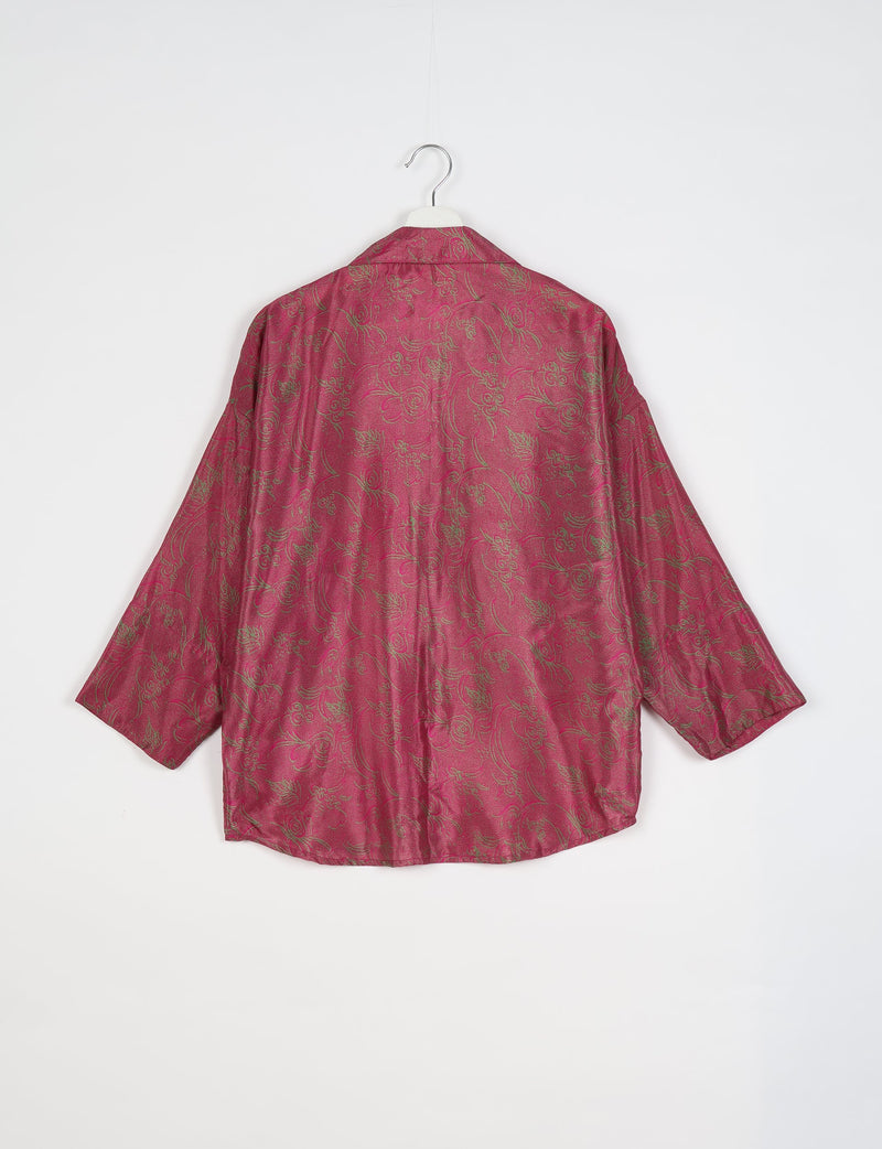 Oversized pink shirt with green tropical floral pattern, long sleeves, and spread collar, shown from back on hanger