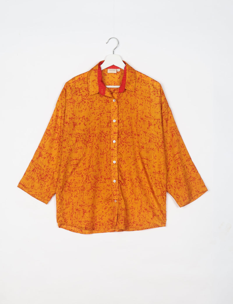 Oversized orange shirt with red abstract pattern, button front, and red inner collar, hanging on white hanger