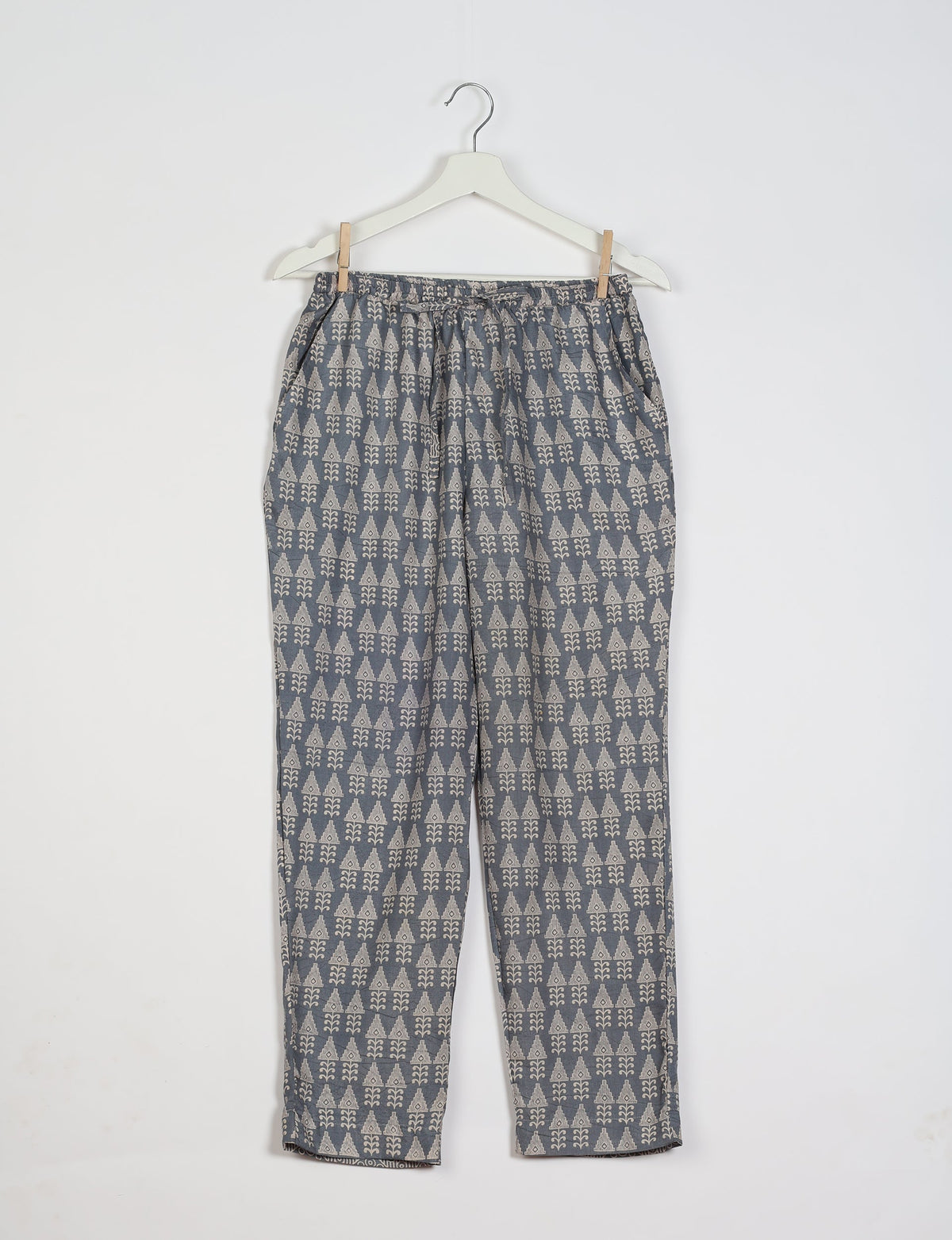 Grey pull-on pants with beige geometric pattern, elastic waistband, and side pockets, hanging on white hanger