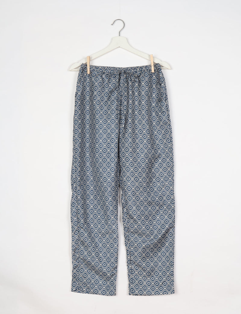 Grey pull-on pants with white geometric wave and circle pattern hanging on white hanger against white background