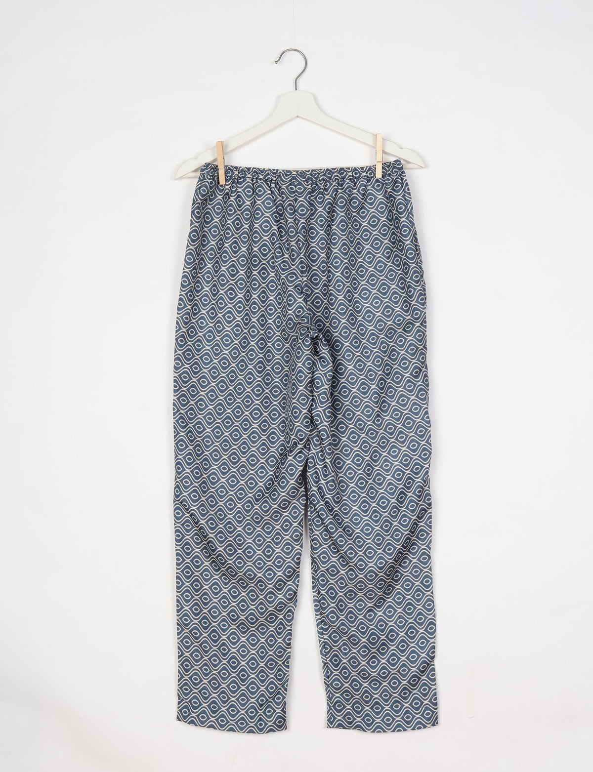 Grey pull-on pants with white geometric wave pattern, elastic waistband, hanging on white hanger against white background