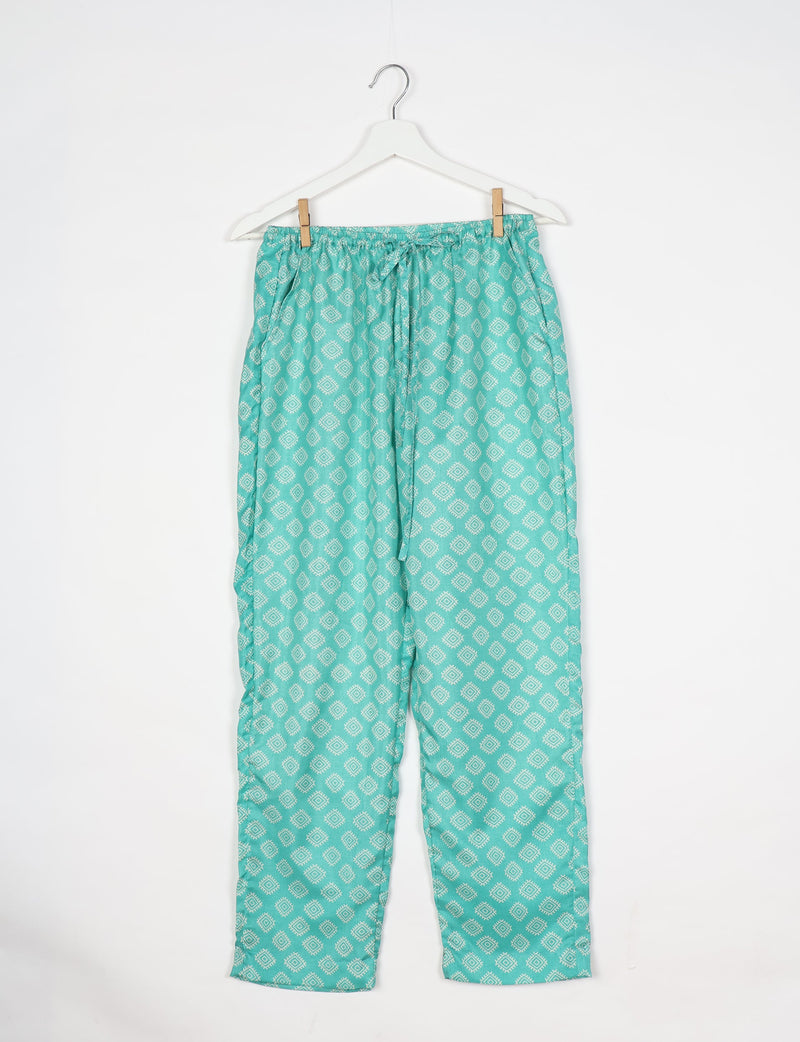 Green pull-on pants with white geometric diamond pattern, elastic waistband, and drawstring, hanging on white hanger
