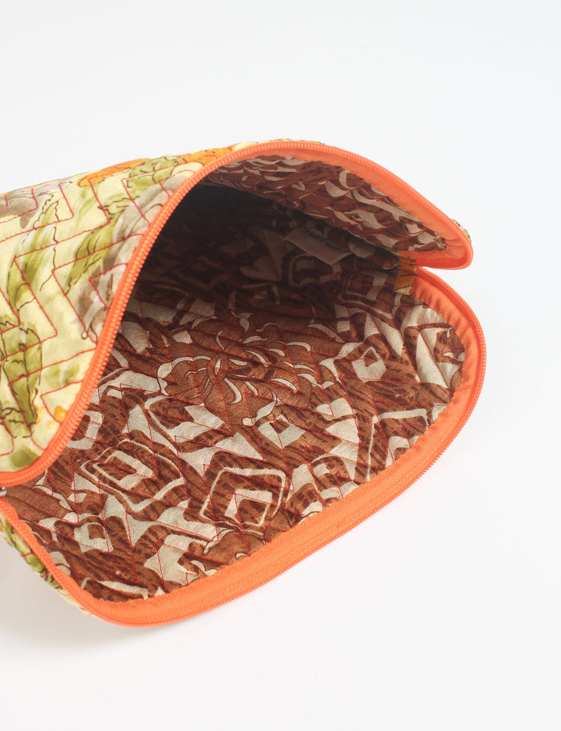 Quilted laptop sleeve with yellow floral exterior, orange zipper, and brown patterned fabric interior, open top view