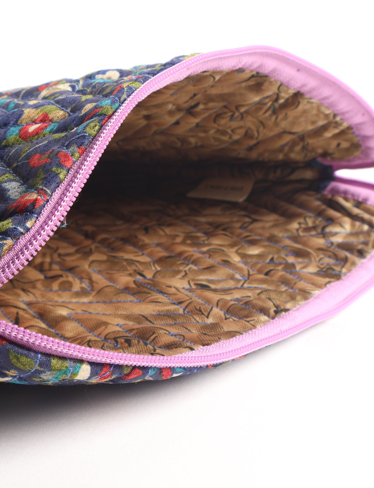 Quilted laptop sleeve with purple paisley exterior, red patterned interior, and light blue zipper, partially open showing label