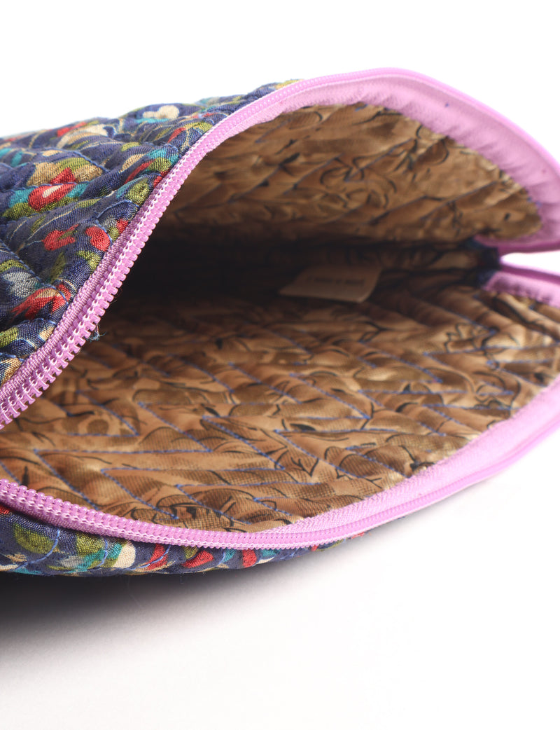 Quilted laptop sleeve with purple paisley exterior, red patterned interior, and light blue zipper, partially open showing label