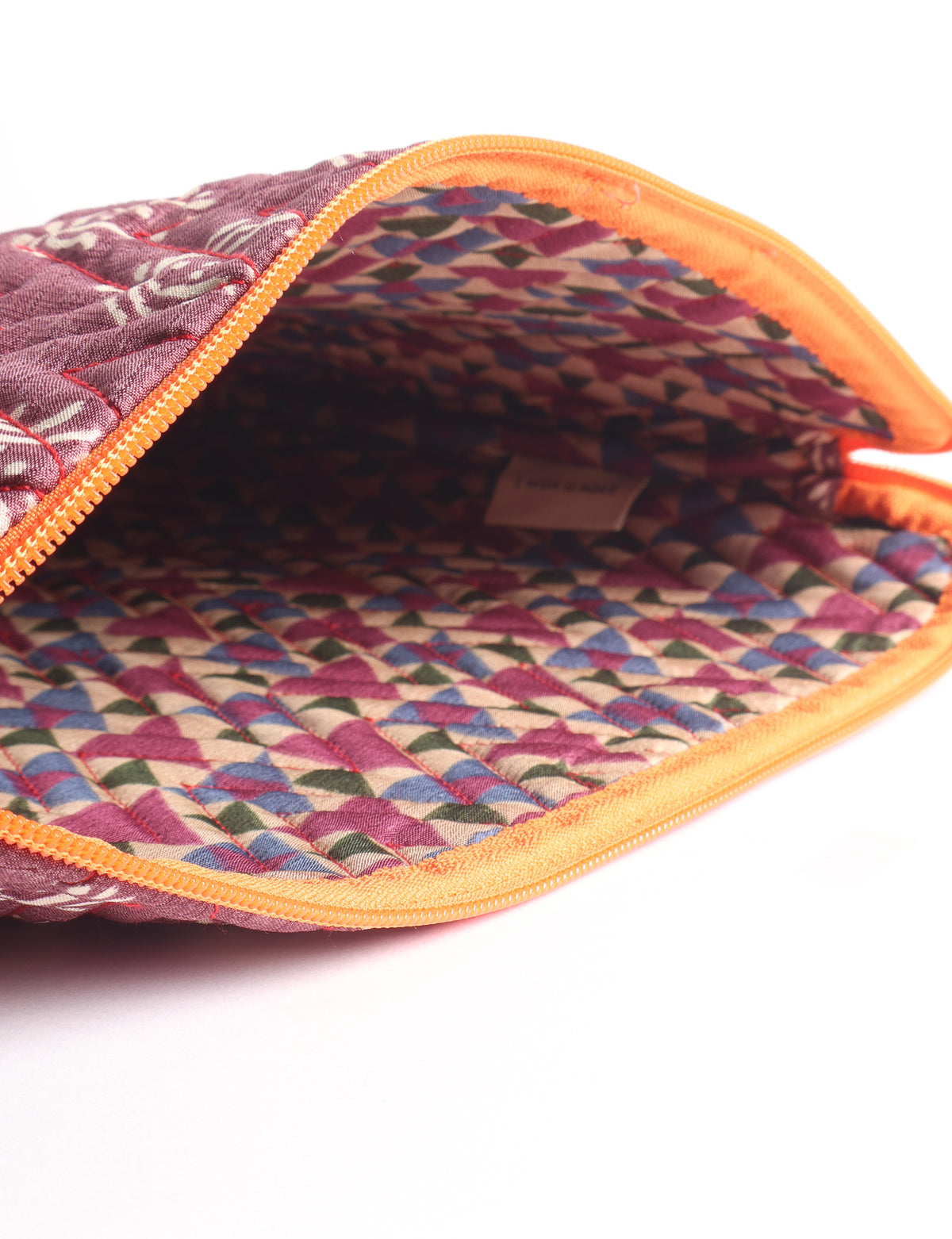 Quilted laptop sleeve with purple paisley exterior, red patterned interior, and light blue zipper, partially open showing label