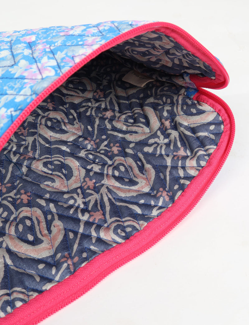 Quilted laptop sleeve with blue floral exterior, pink zipper trim, and dark patterned fabric interior, shown open