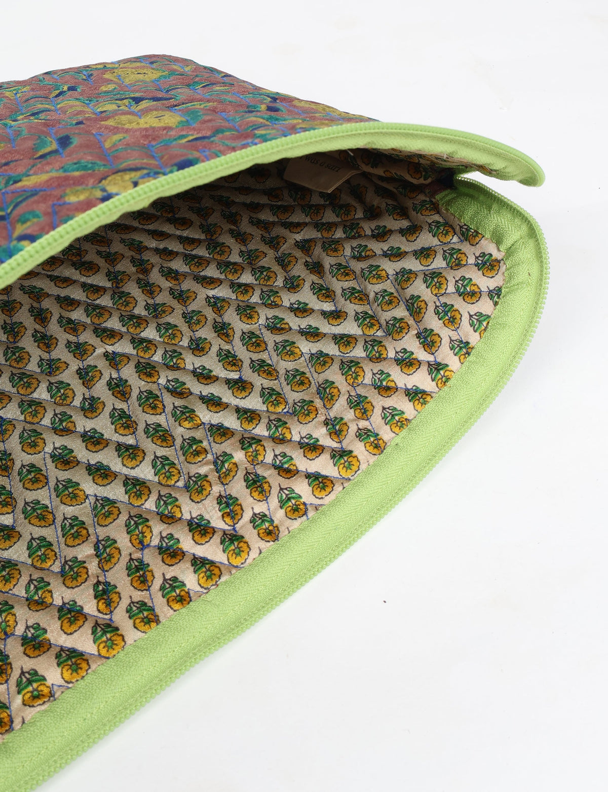 Quilted laptop sleeve with brown floral exterior, green zipper trim, and beige interior with small yellow flower print