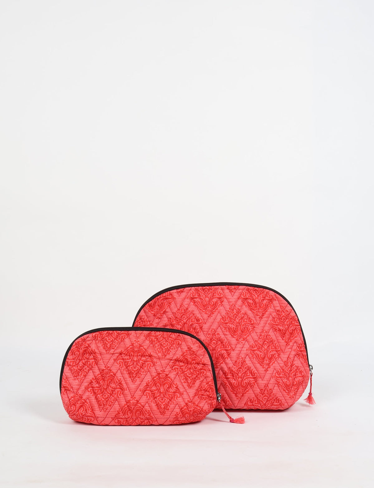 Set of two pink tropical patterned quilted vanity pouches with black trim and tassel zipper pulls, front view on white background