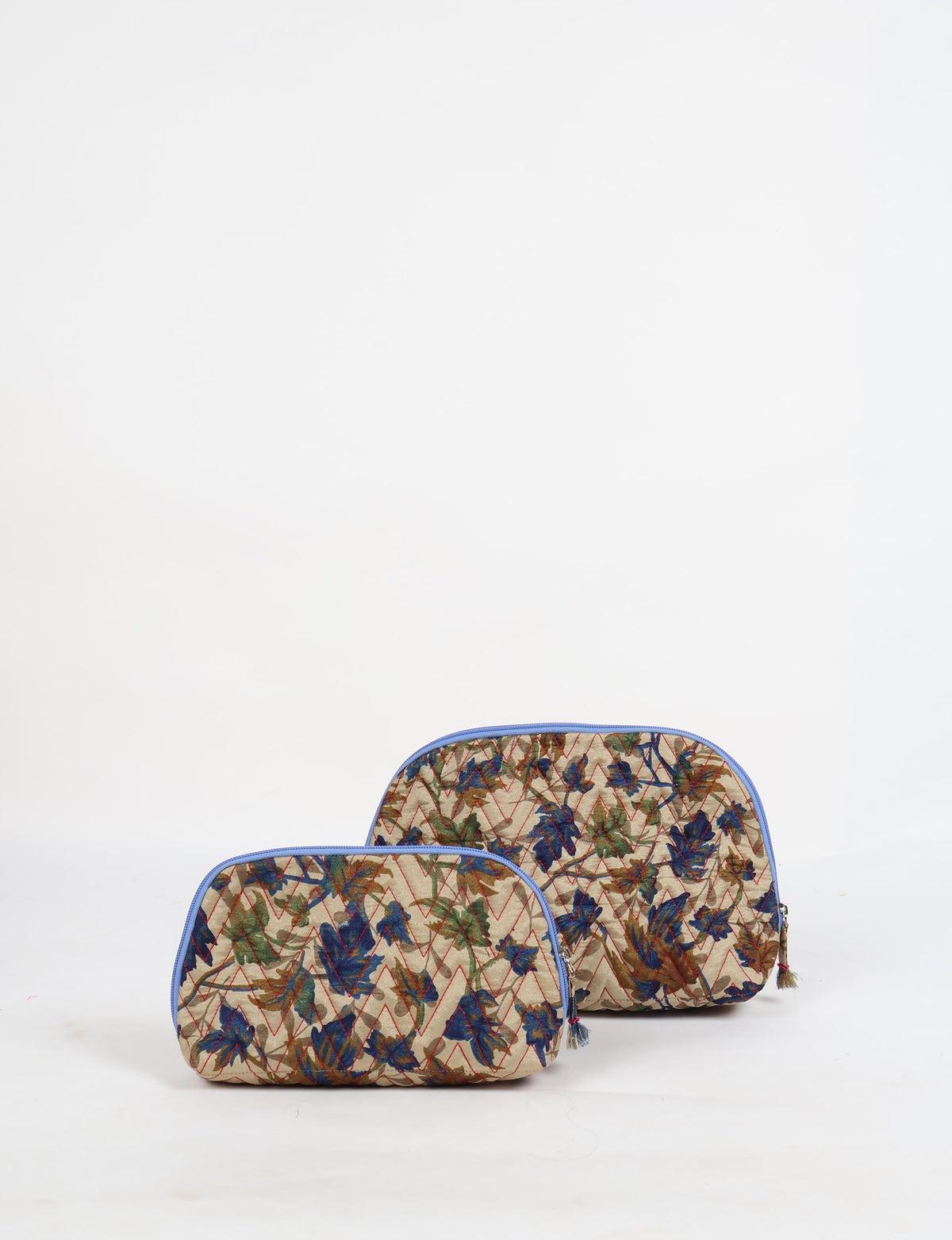 Set of two beige quilted vanity pouches with blue, green, and brown leaf patterns and blue zipper trims, front view