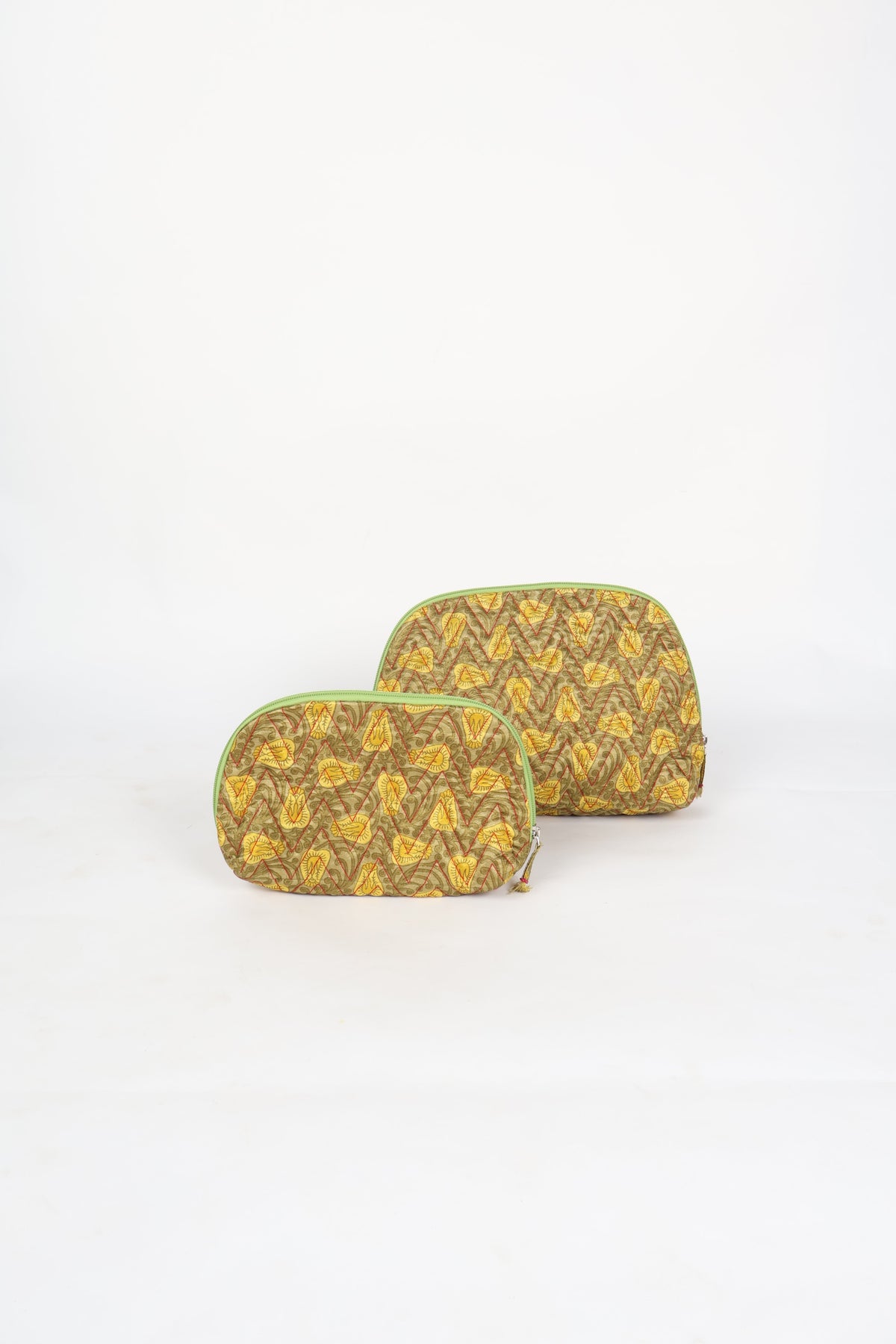 Two yellow tropical patterned quilted vanity pouches with green zipper edges, shown flat on white background