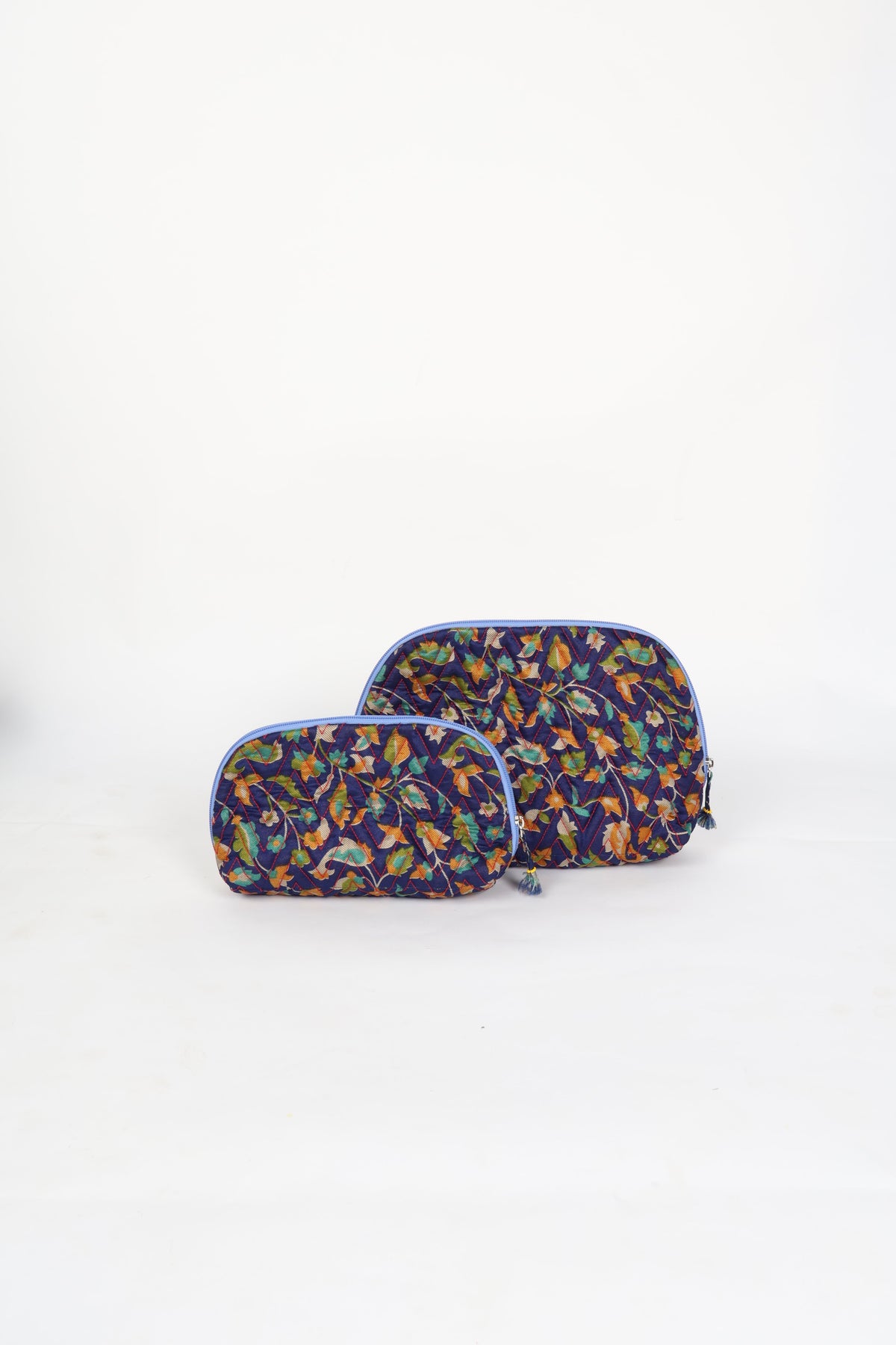 Blue tropical quilted cotton vanity pouch set with zipper and tassel details, front view, standing on white background