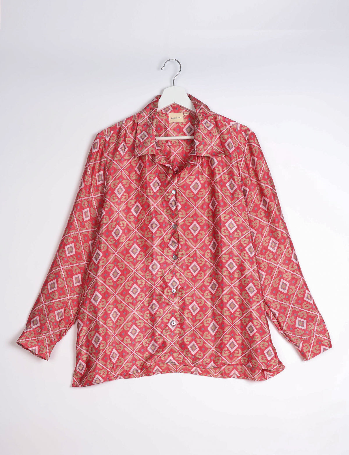 Pink geometric patterned long-sleeve resort shirt with collar and buttons, hanging on white hanger against white background