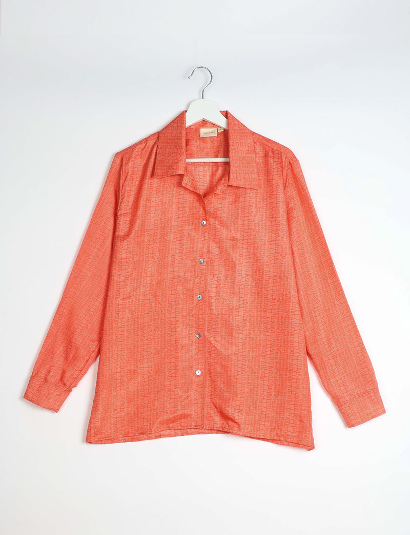 Orange resort shirt with abstract pattern, long sleeves, button front, and spread collar, hanging on white hanger