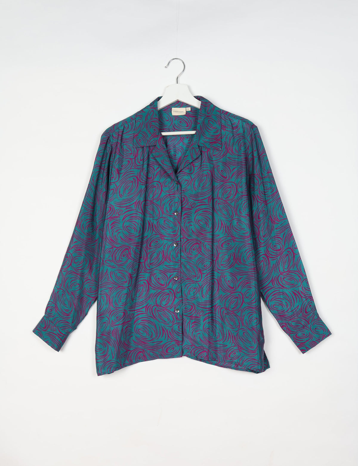Blue resort shirt with abstract purple swirl pattern, long sleeves, and button front, hanging on white hanger