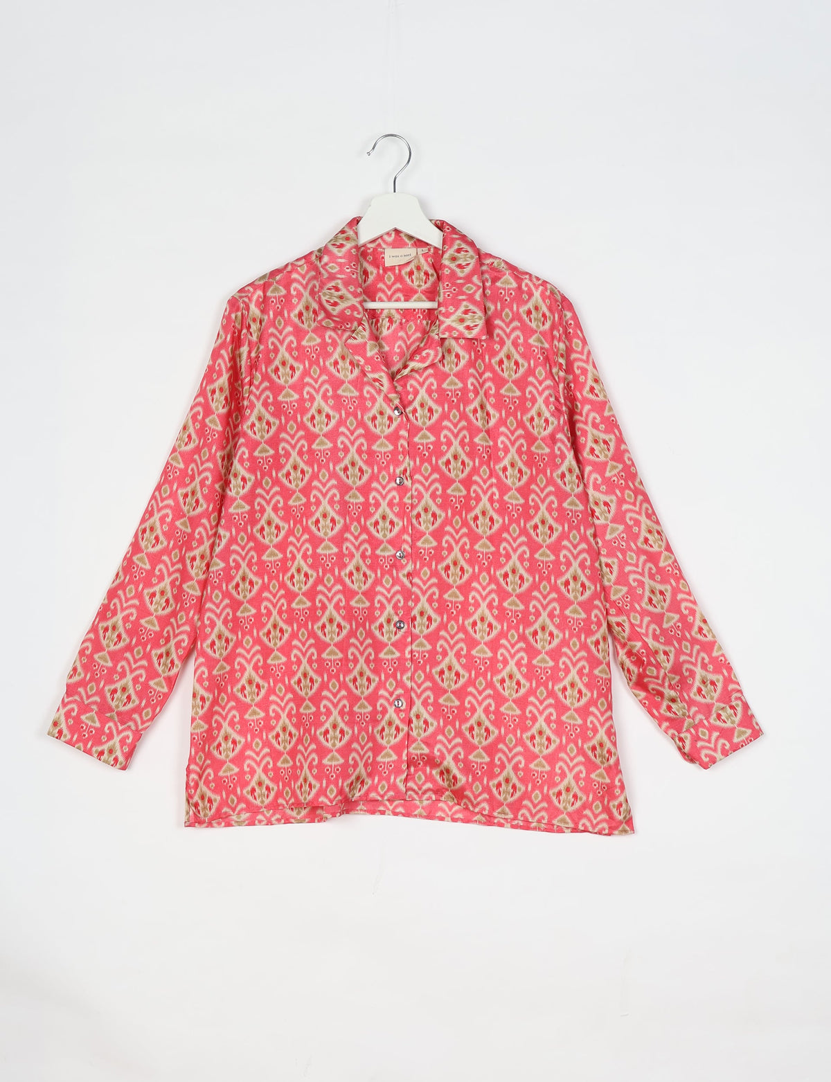 Pink long-sleeve resort shirt with Indian ethnic pattern, button front, and notched collar, hanging on white hanger