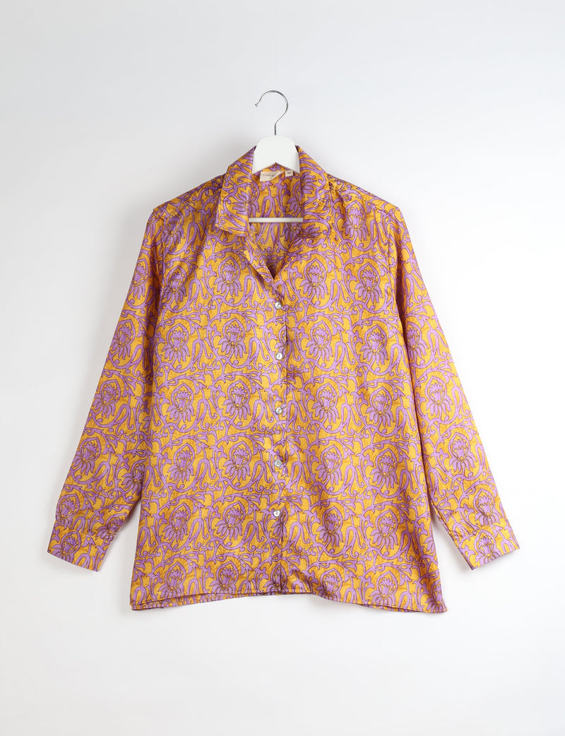 Yellow and purple abstract patterned long-sleeve button-up resort shirt hanging on white hanger against white background