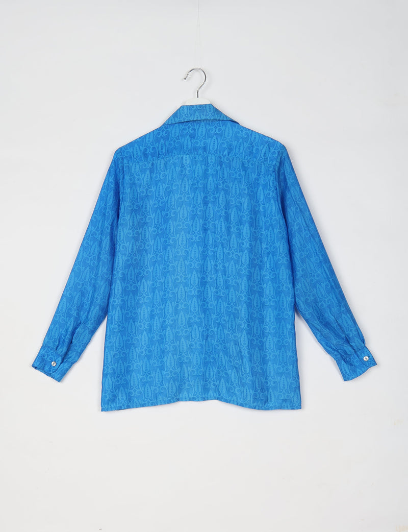 Blue long-sleeve resort shirt with tropical pattern, buttoned cuffs, and spread collar, shown from back on hanger