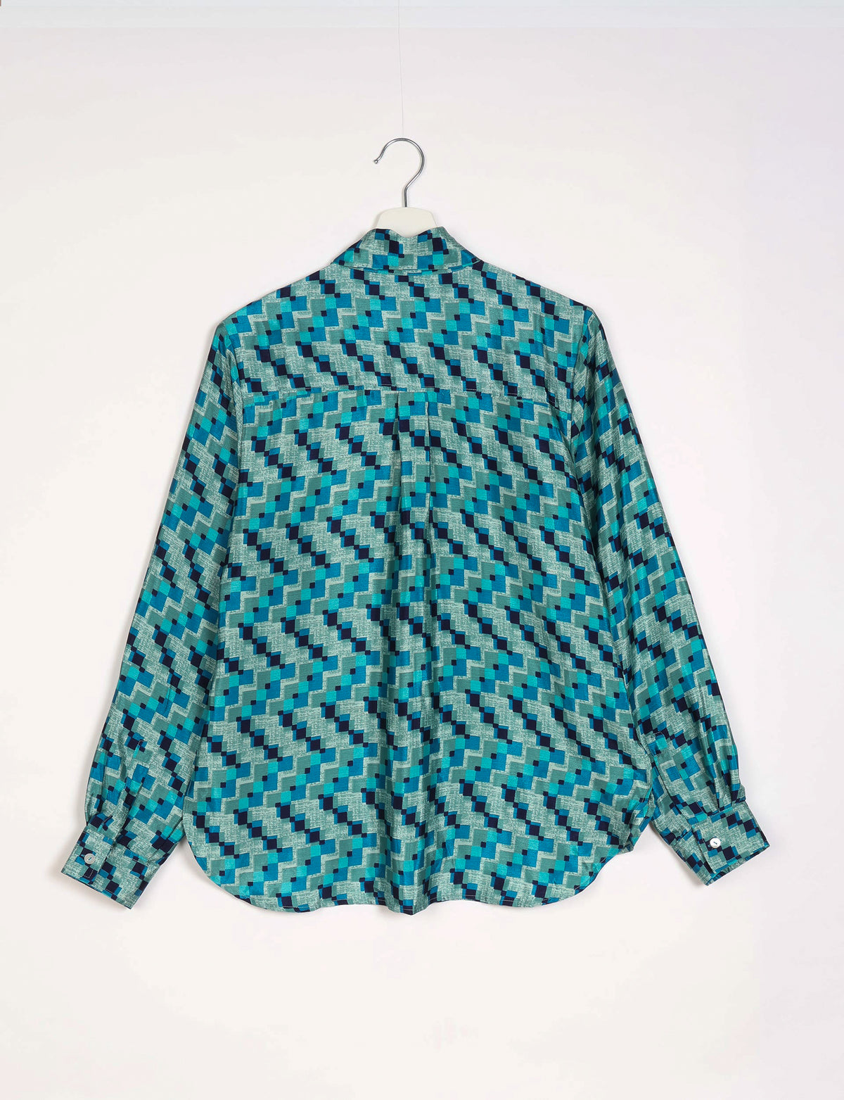 Blue geometric patterned long-sleeve shirt with buttoned cuffs hanging on white hanger, back view