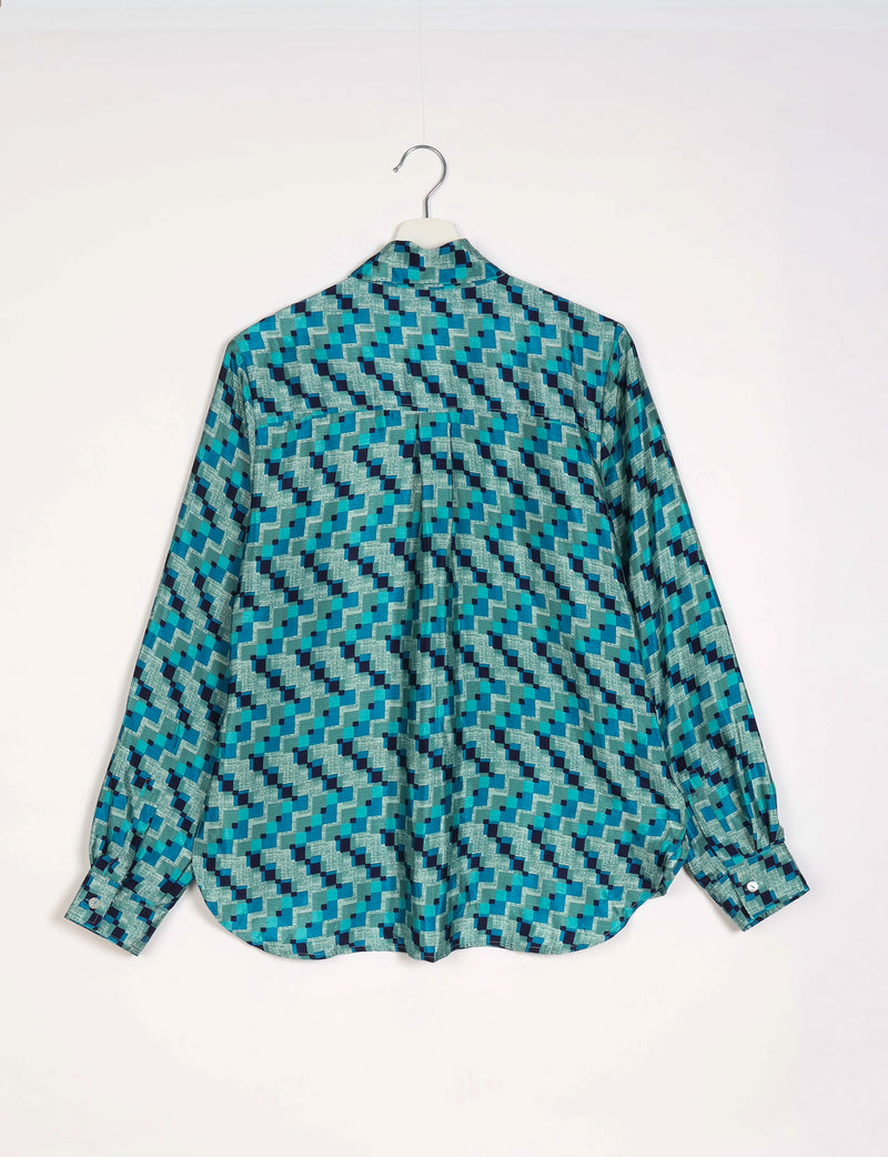 Blue geometric patterned long-sleeve shirt with buttoned cuffs hanging on white hanger, back view