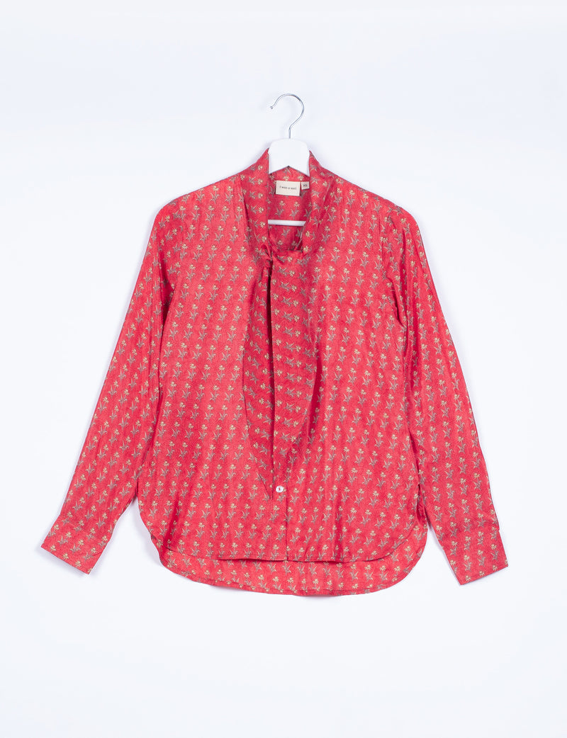 Long-sleeve orange shirt with micro floral pattern and attached bowtie, hanging on white hanger, size XS tag visible