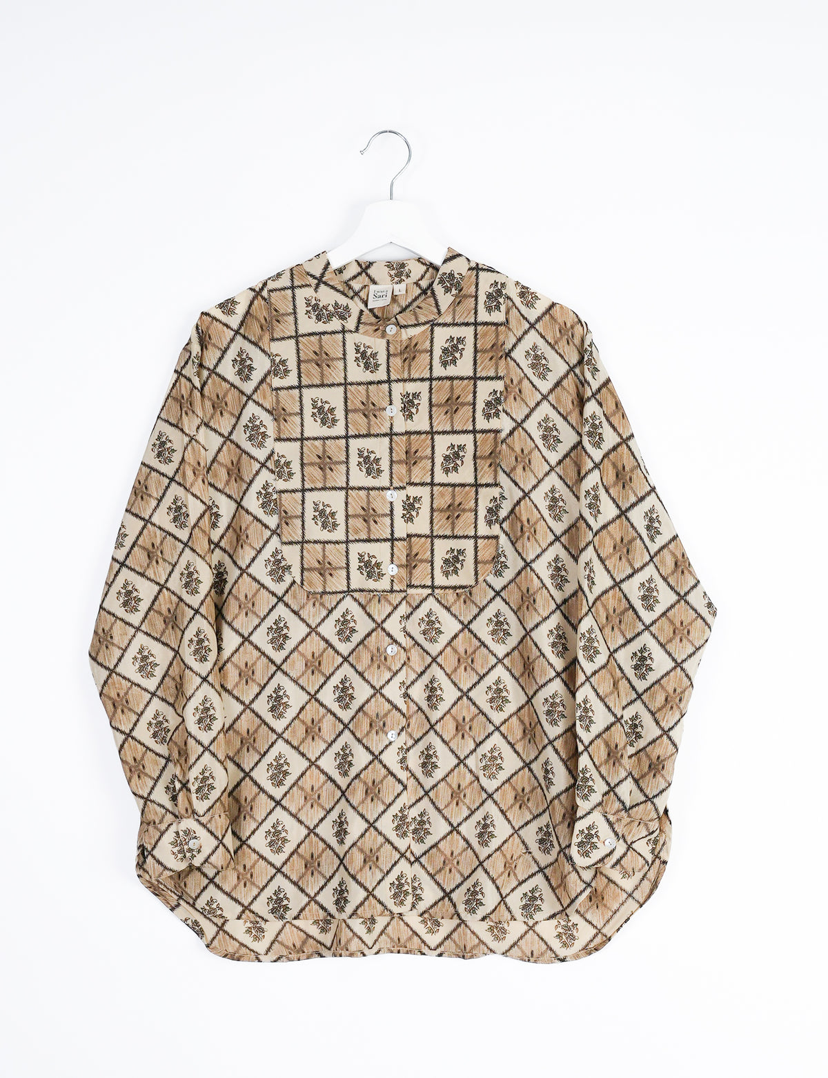 Beige longline shirt with geometric diamond and floral pattern, button front, and cuffed sleeves hanging on white hanger
