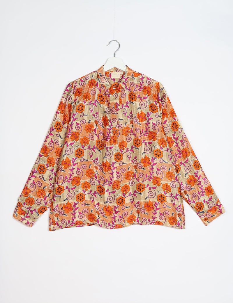 Orange floral patterned blouse with long sleeves and a collar, hanging on a white hanger against a white background