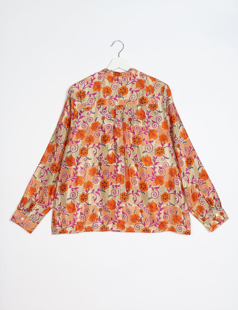 Long-sleeve blouse with orange floral and purple vine print on beige checkered background, shown from back on white hanger