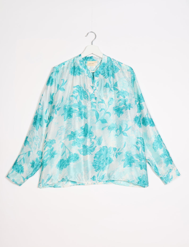 Blue floral patterned long-sleeve blouse with mandarin collar, button placket, and cuffed sleeves hanging on white hanger
