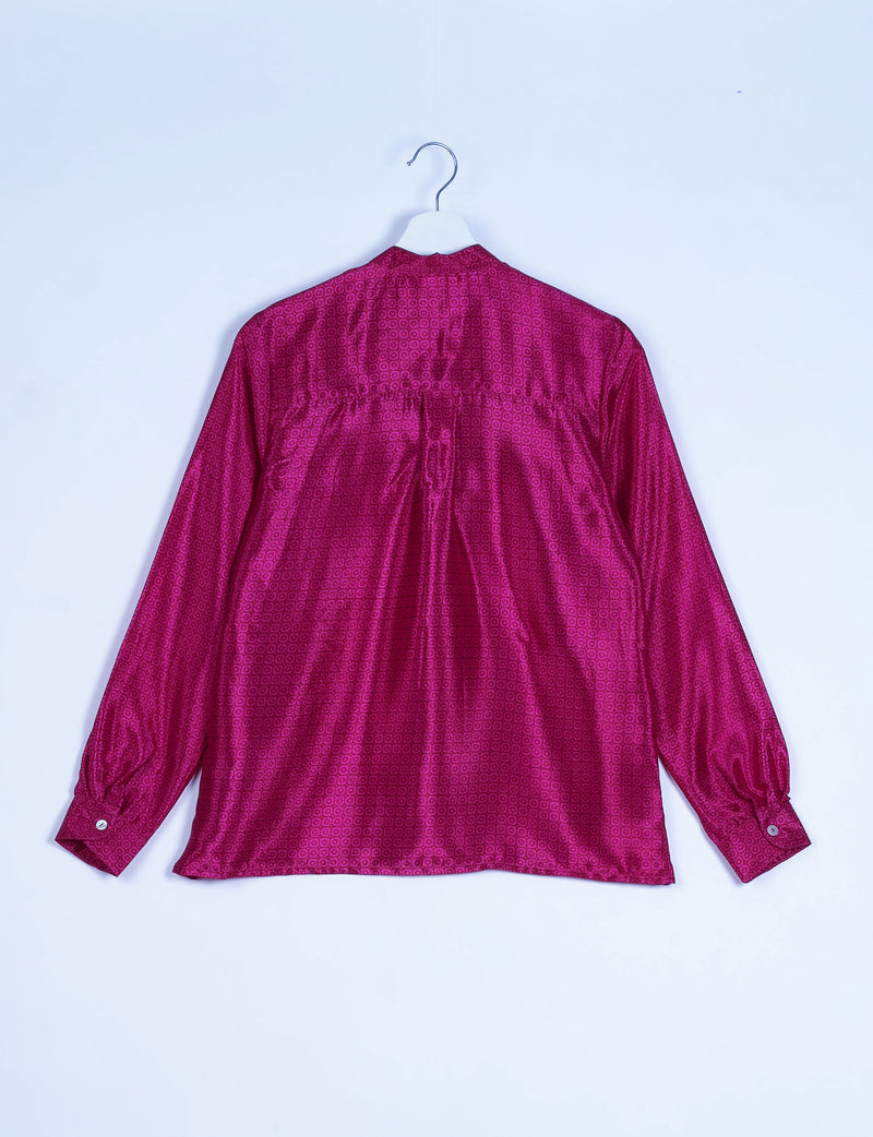 Pink blouse with micro geometric pattern, long sleeves with buttoned cuffs, shown from back on white hanger