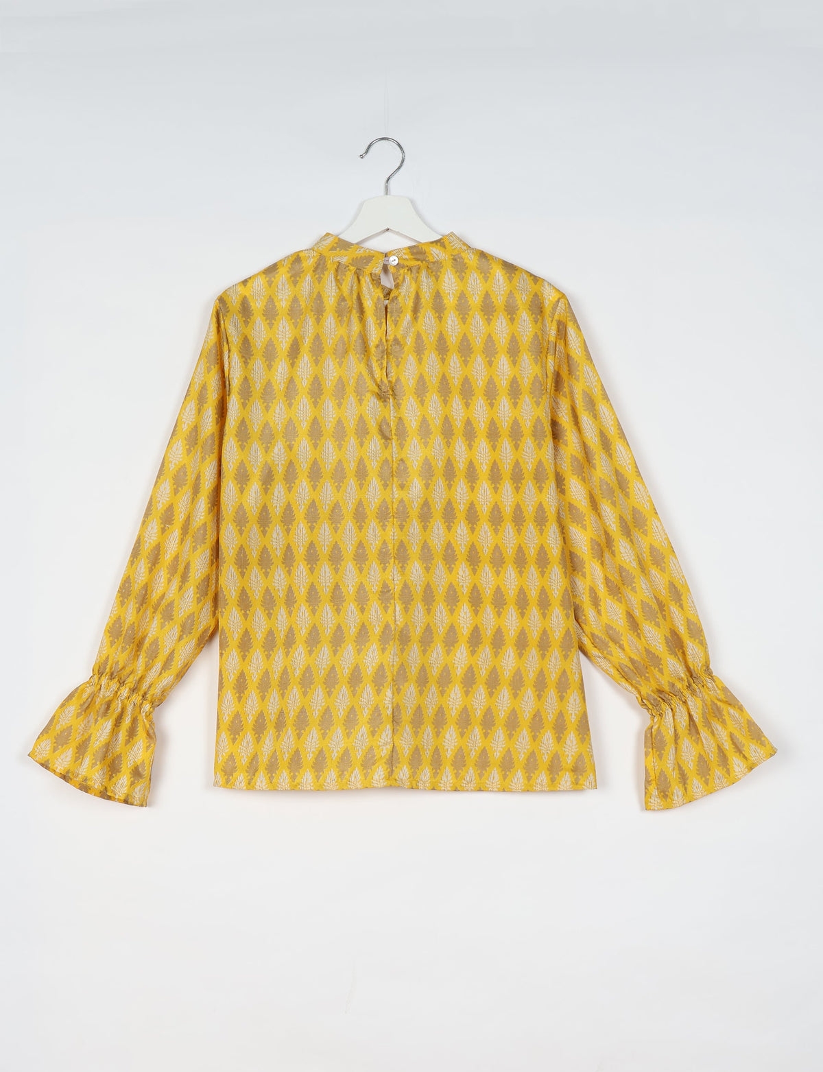 Yellow blouse with beige leaf diamond pattern, long sleeves with gathered cuffs, and back button closure, shown hanging flat