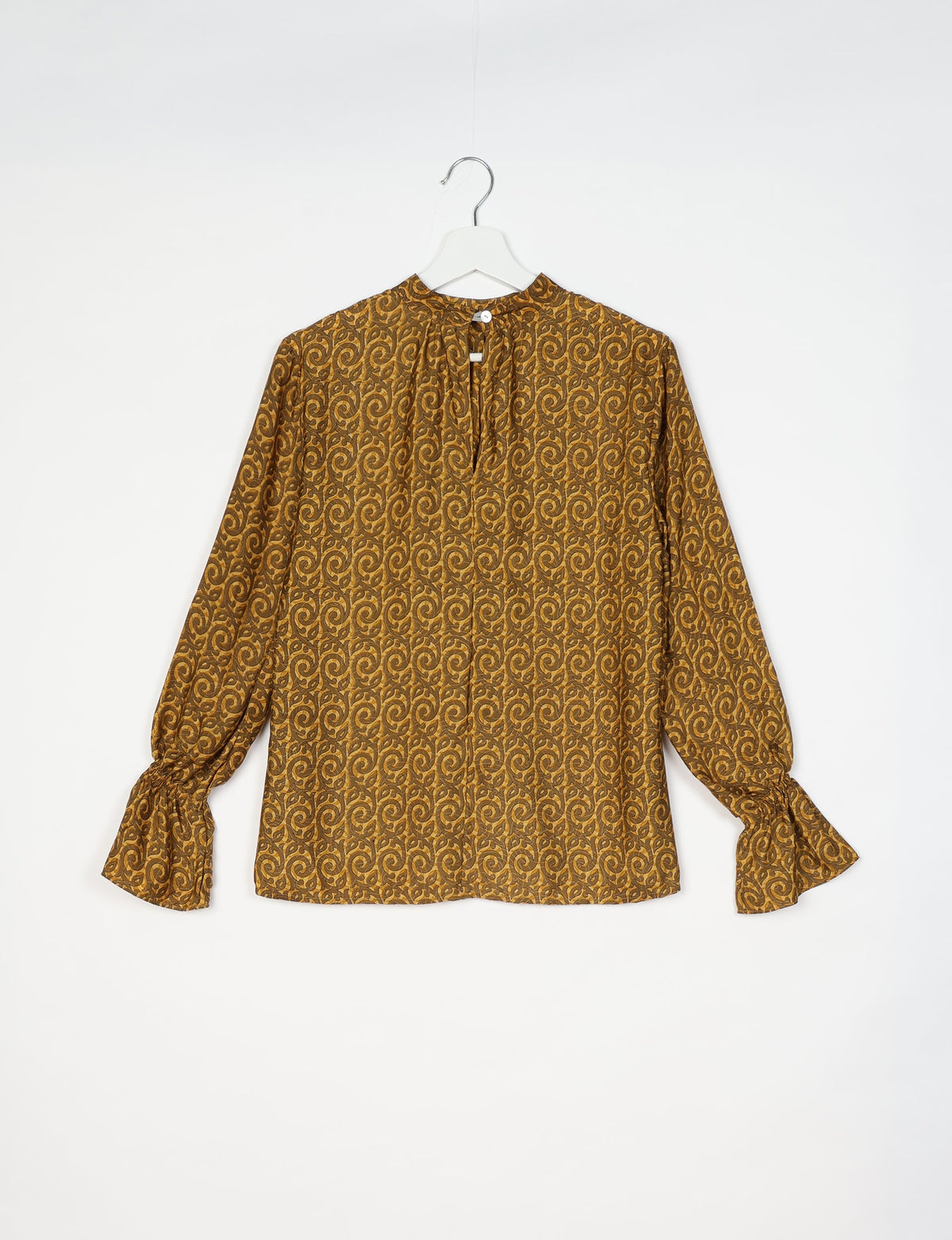 Yellow abstract patterned flowing blouse with long sleeves and button closure at the back, shown on hanger