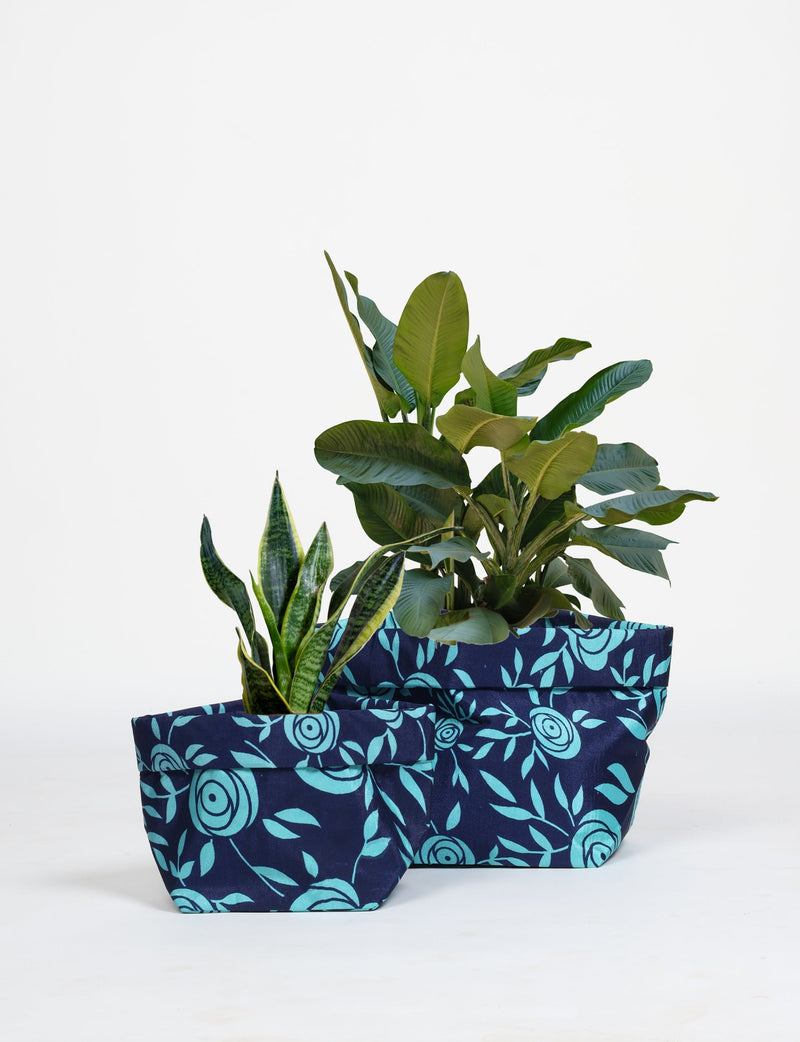 Two blue floral fabric plant pot covers with waterproof lining, shown with green plants, in small and medium sizes