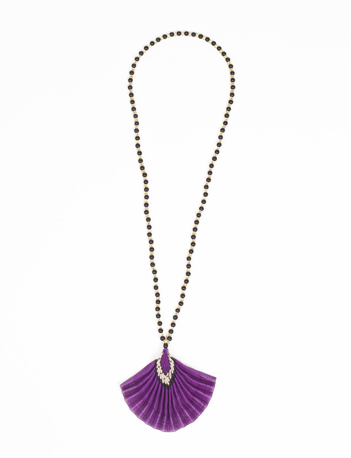 Necklace with black and gold beads and a pleated purple abstract fan-shaped pendant, flat lay on white background