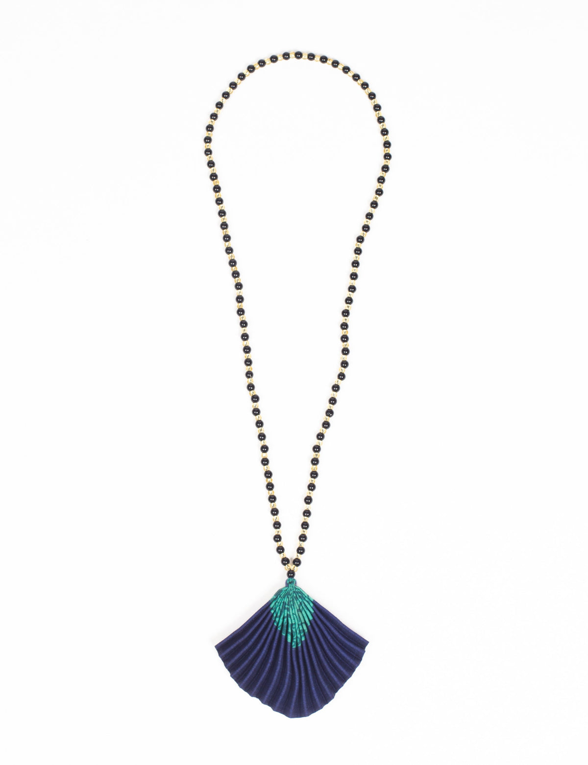 Necklace with black and gold beads and a pleated blue fabric pendant with green abstract pattern, flat lay on white background