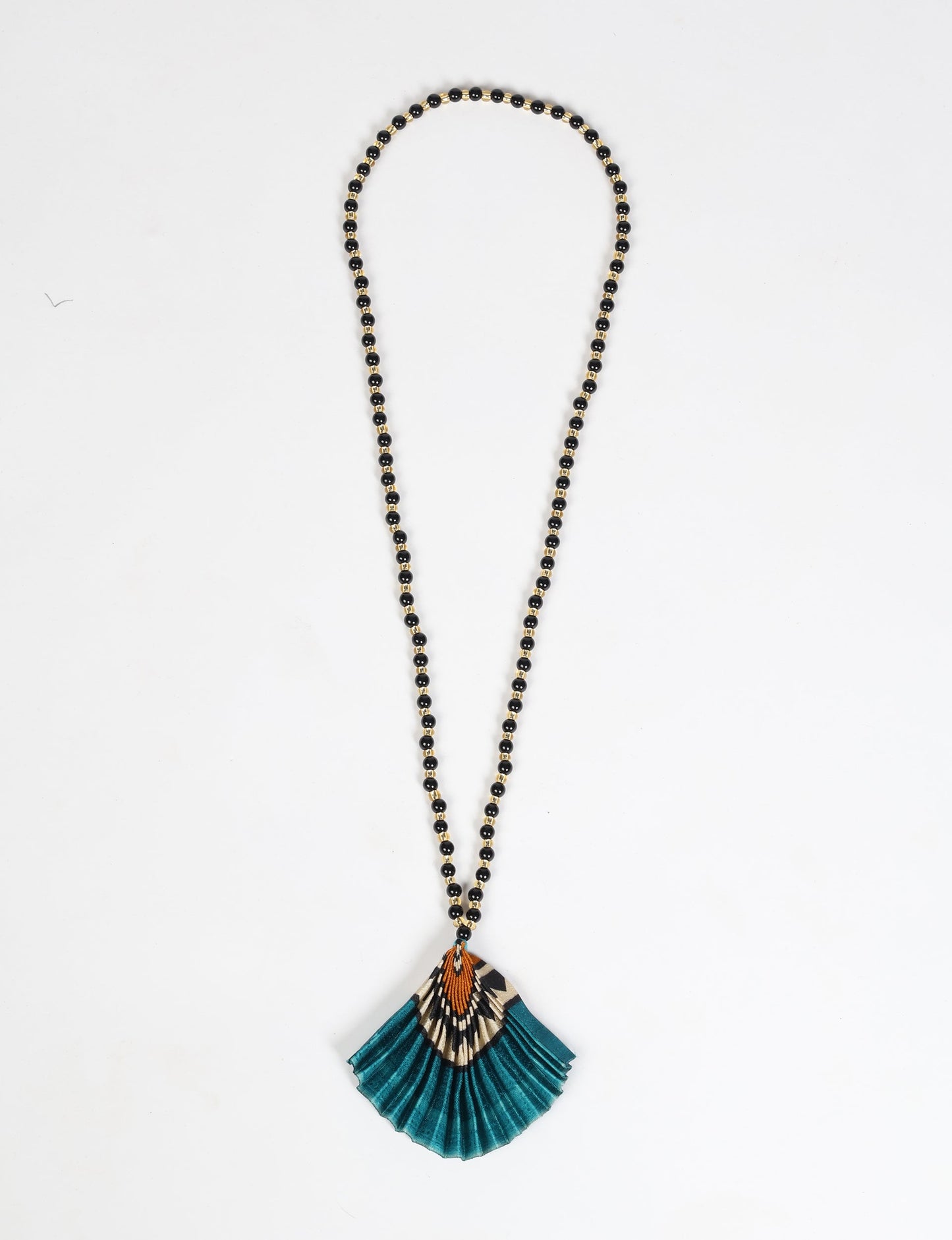 Dive into sustainable fashion with our PLEATED NECKLACE, a creation by talented female artisans in Mumbai. The pleated fan pendant, made from upcycled saris, hangs on a colorful necklace crafted from glass beads, embellished with sparkling glass crystals. An ethical, green fashion statement for conscious styling.