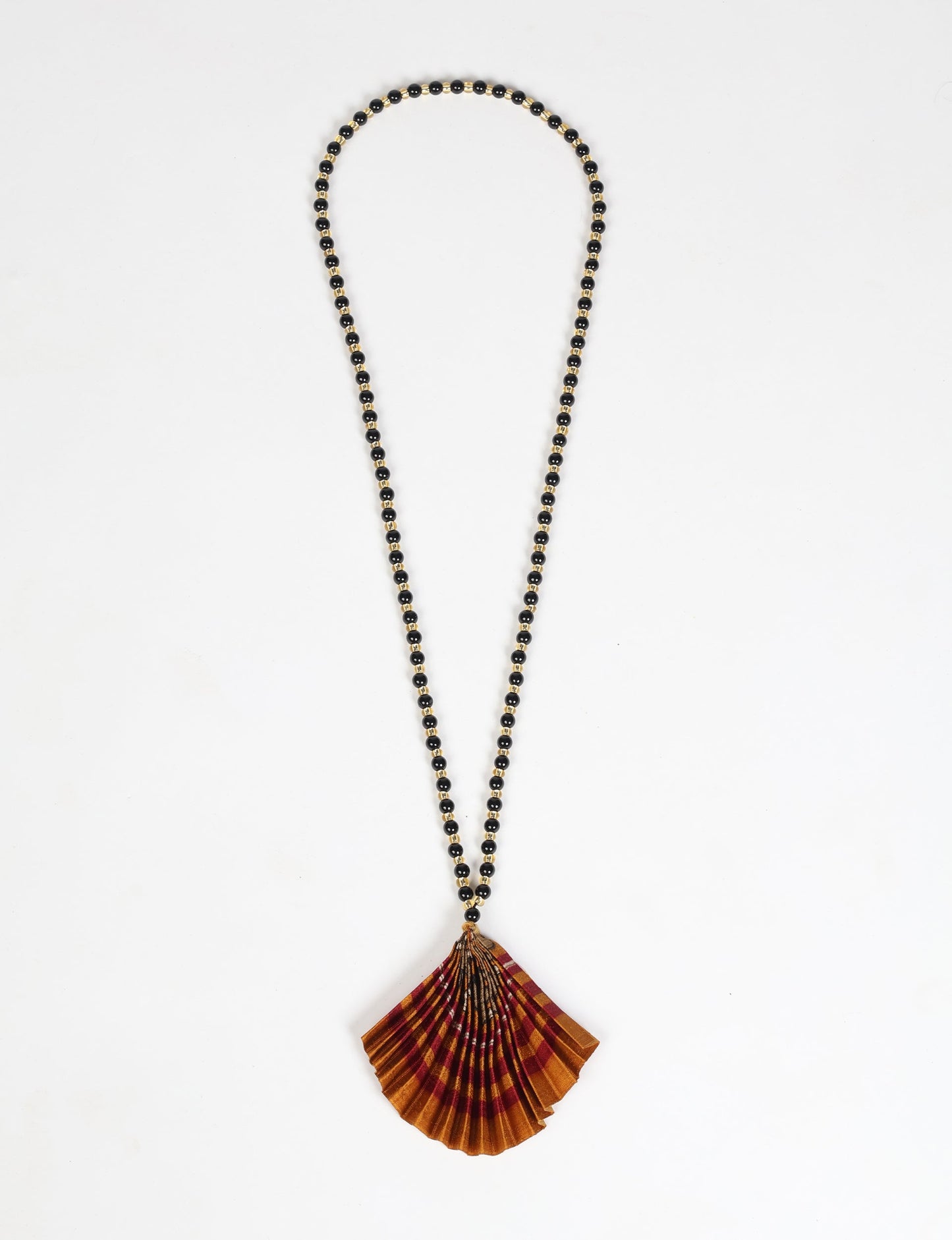 Dive into sustainable fashion with our PLEATED NECKLACE, a creation by talented female artisans in Mumbai. The pleated fan pendant, made from upcycled saris, hangs on a colorful necklace crafted from glass beads, embellished with sparkling glass crystals. An ethical, green fashion statement for conscious styling.