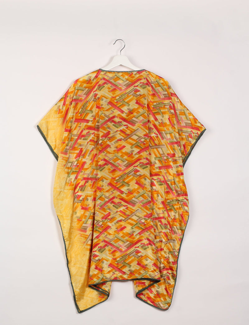 Yellow kaftan with abstract multicolor geometric pattern and dark lace trim on edges, shown hanging from white hanger