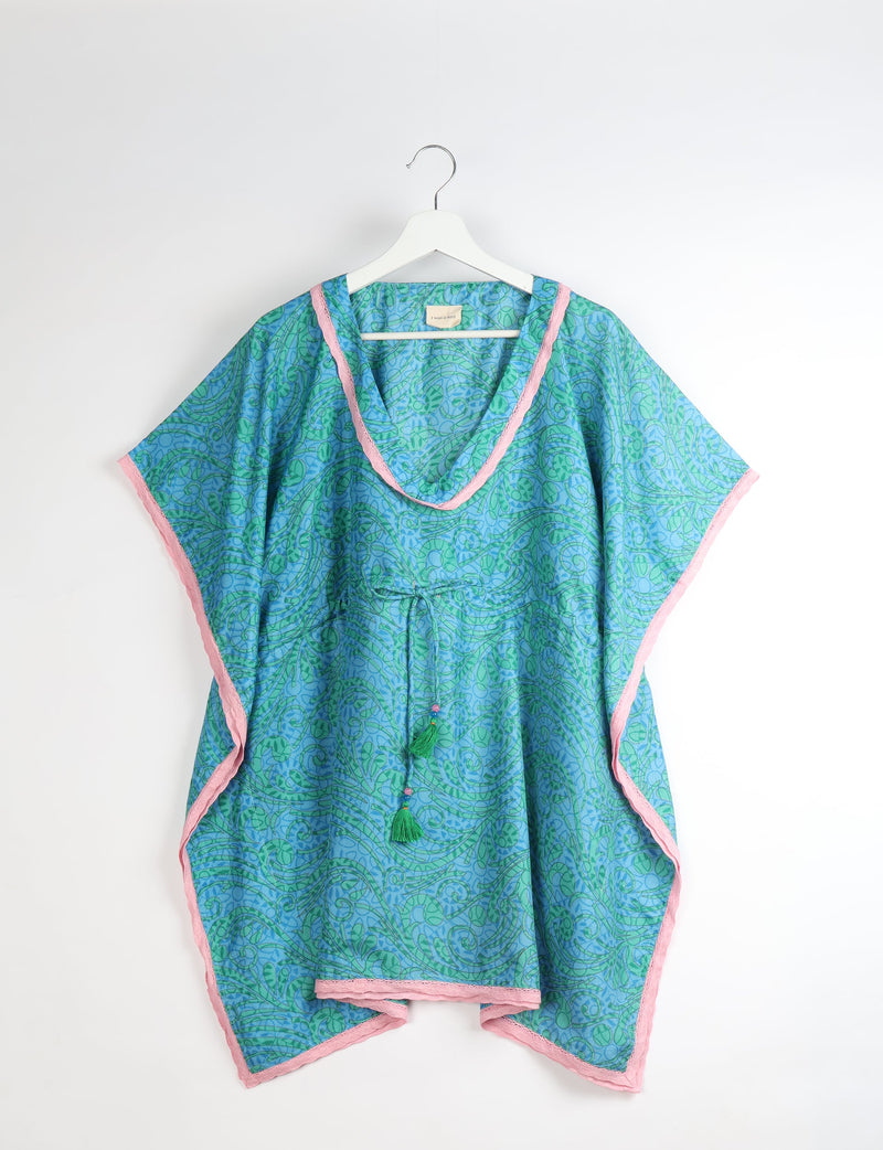 Blue and green abstract patterned short kaftan with pink lace trim, V-neck, and tassel drawstring, hanging on white hanger