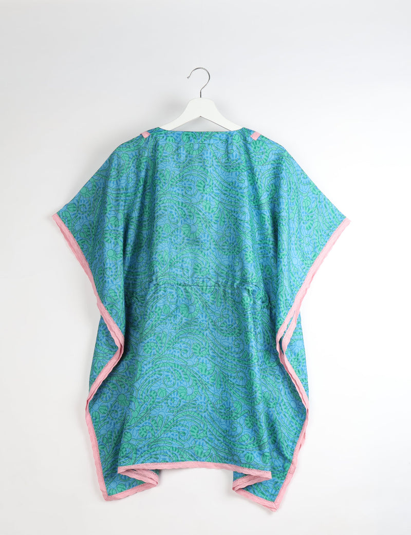 Blue and green abstract patterned short kaftan with pink lace trim, shown hanging on white hanger, back view