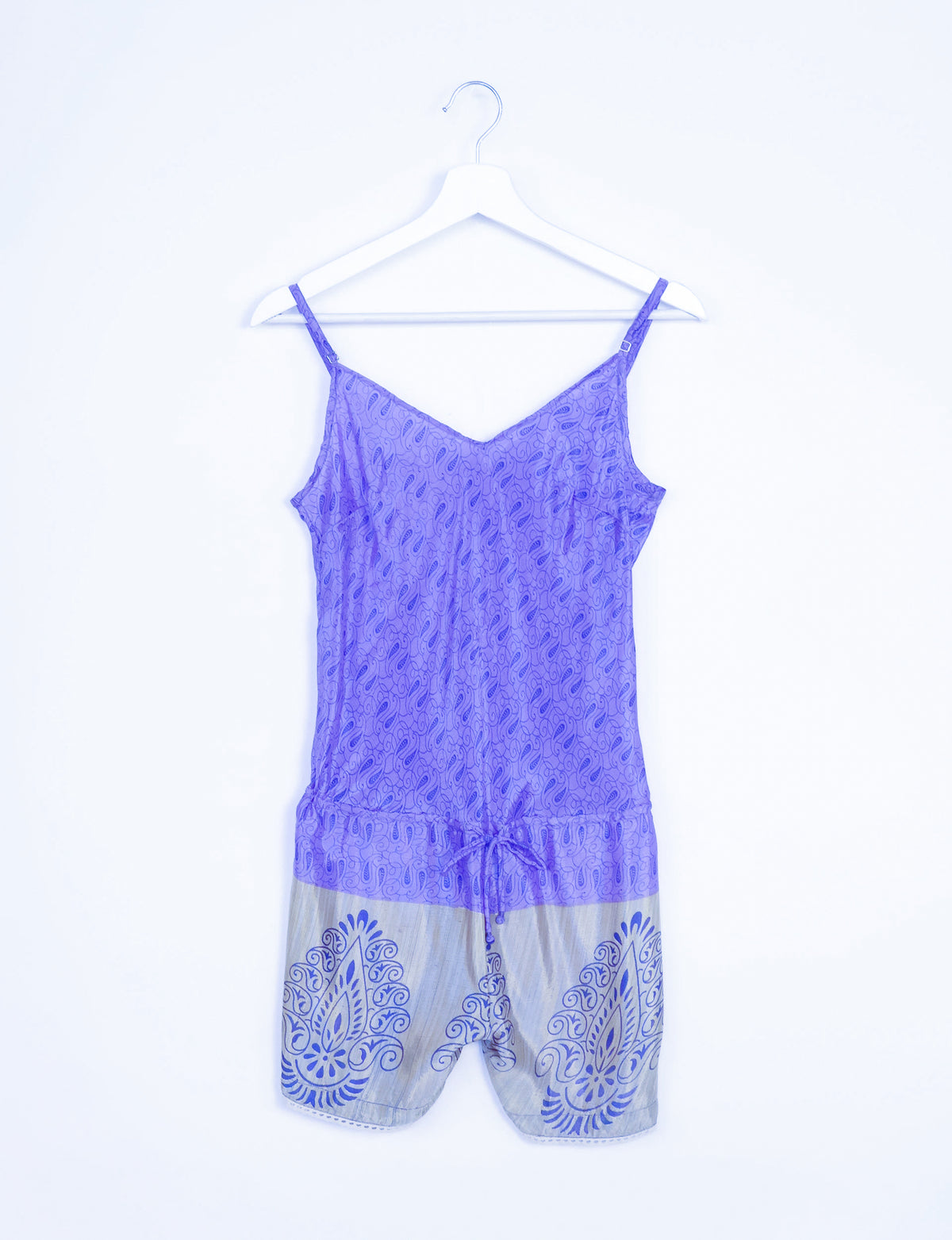 Purple playsuit with adjustable straps, micro paisley lace design on top, and blue patterned shorts, hanging on white hanger