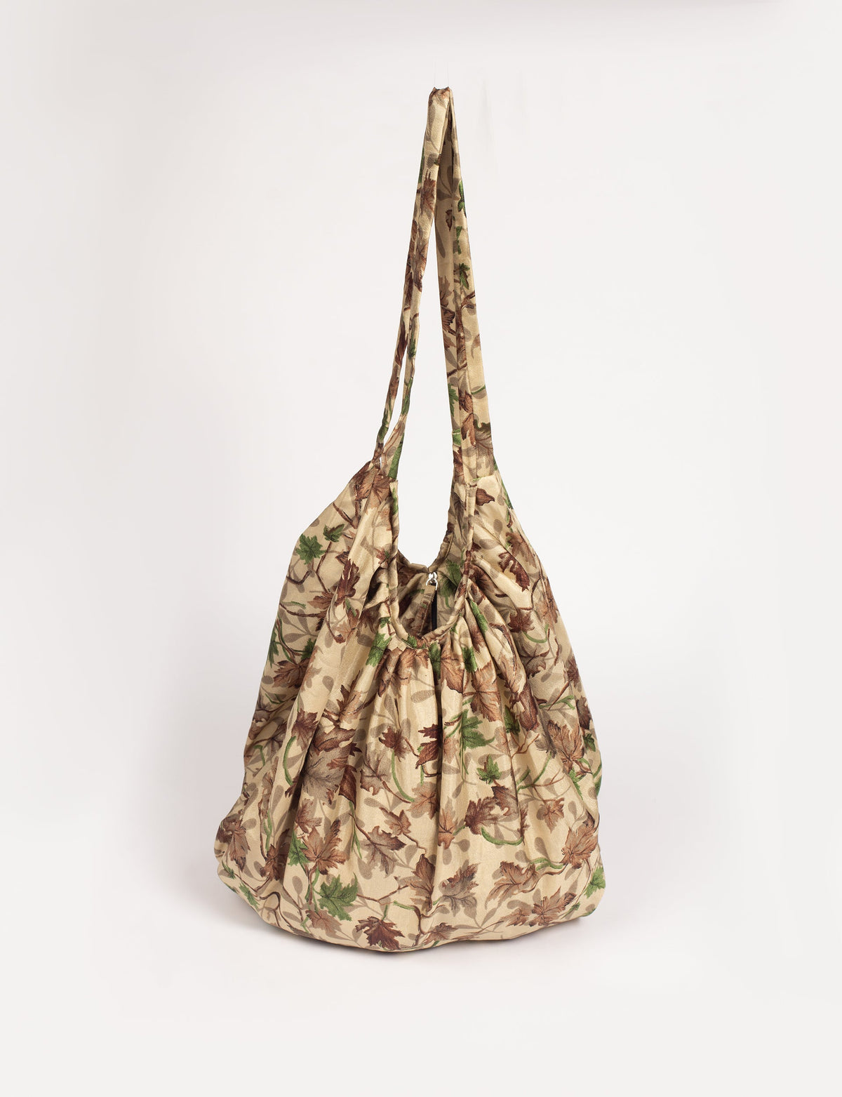 Beige tropical print hobo bag with gathered top and long shoulder straps, front view hanging against white background