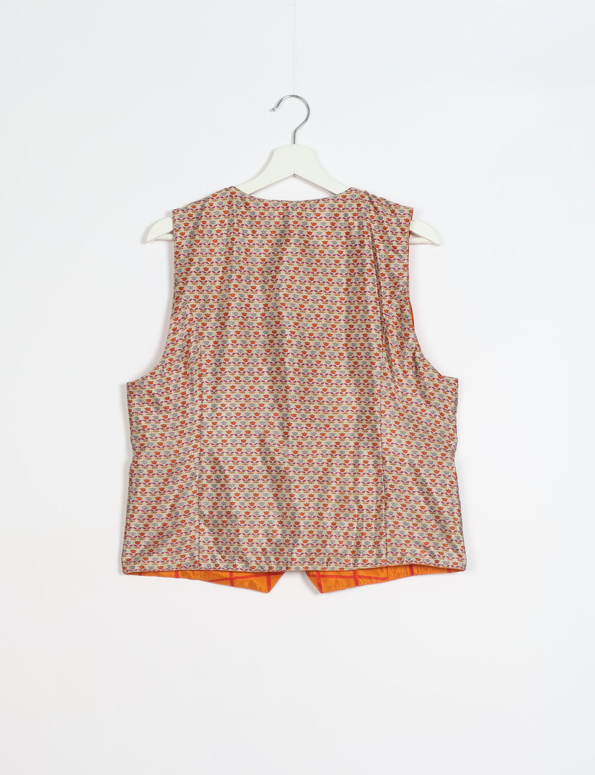 Beige waistcoat with small multicolor floral pattern, sleeveless, shown from back on white hanger against white background